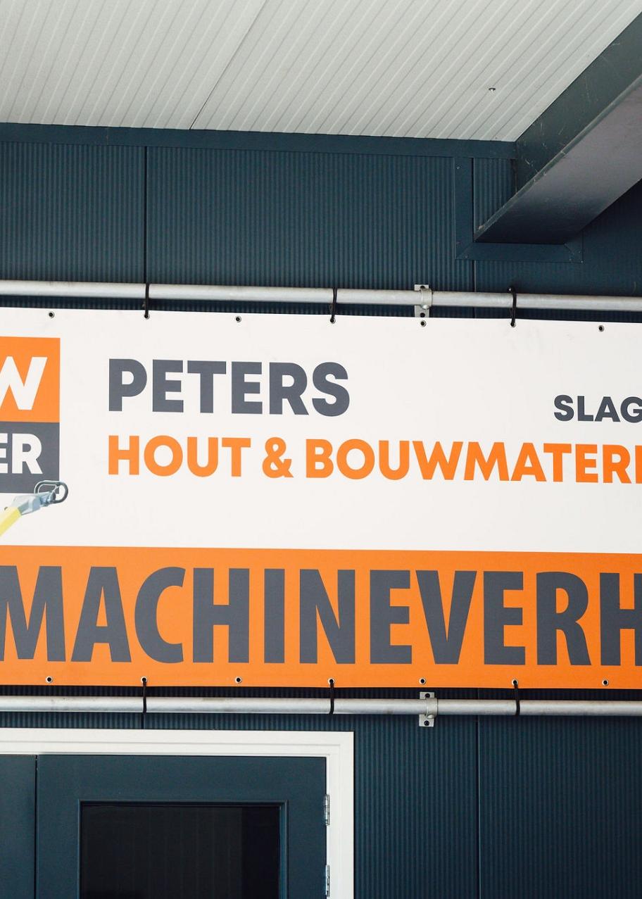 BouwPartner Peters in Slagharen biedt hout, bouwmaterialen en machineverhuur aan, weergegeven op een reclamebord boven hun ingang.
