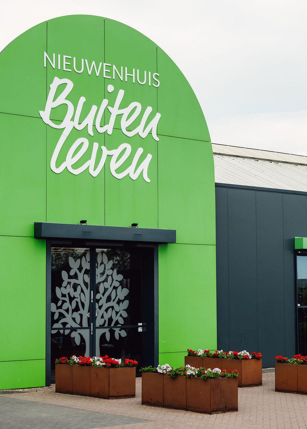 Entree van Nieuwenhuis Buitenleven met groene gevel en bloembakken