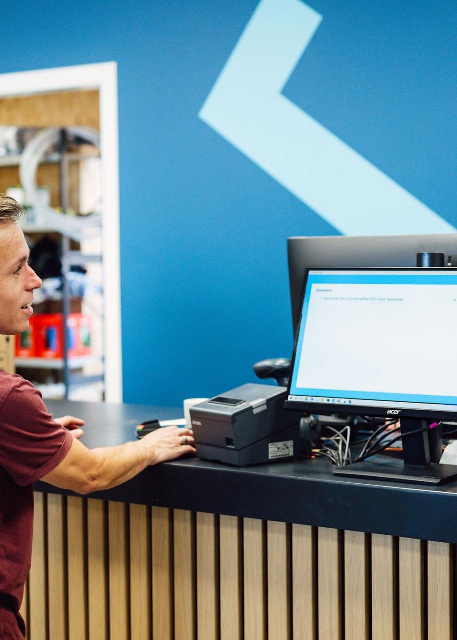 Een man staat aan de voorkant van een kassa af te rekenen met een medewerker achter de kassa. 