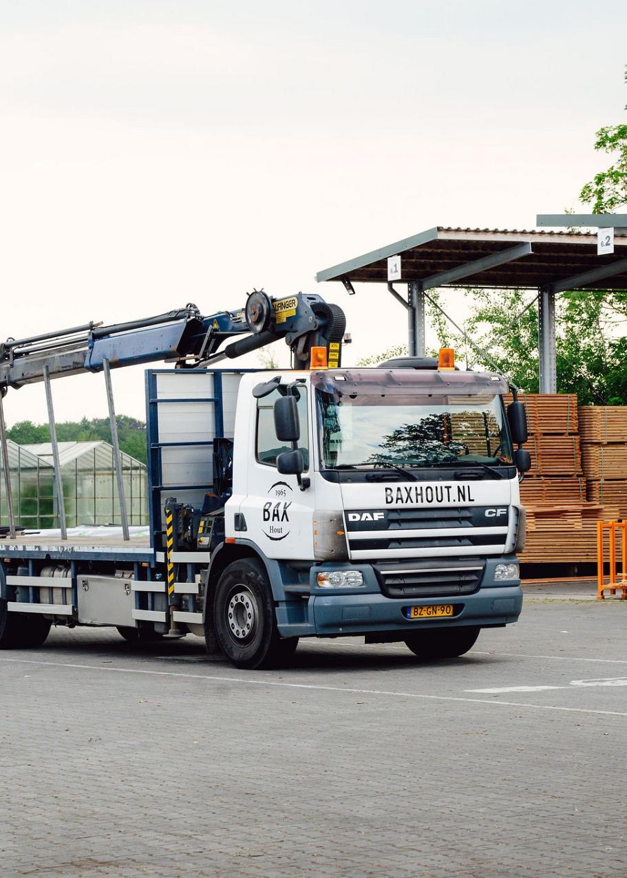 Vrachtwagen en heftruck met op de achtergrond grote pallets met hout.