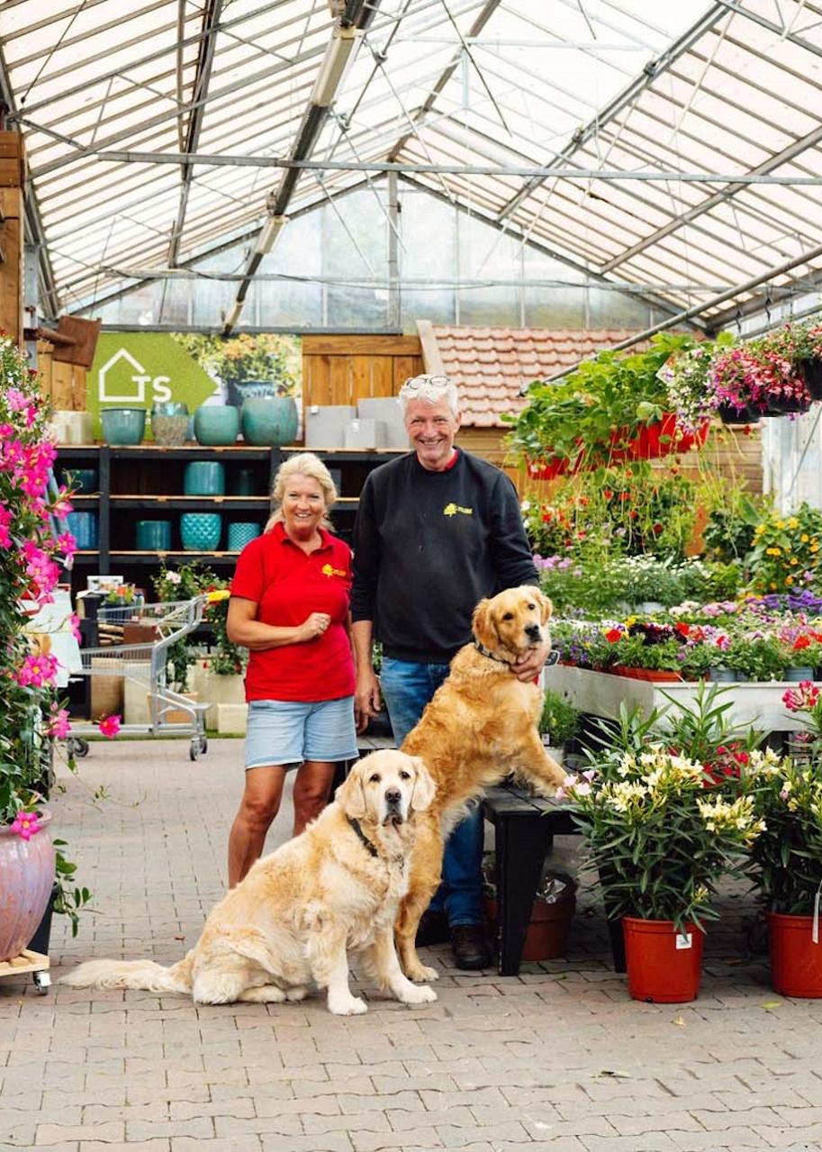 Man en vrouw met 2 honden in een tuincentrum.