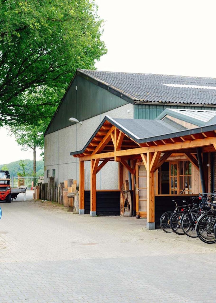 Voorkant van bedrijvenpand met houten voorgevel, fietsenstalling en op de achtergrond een heftruck.