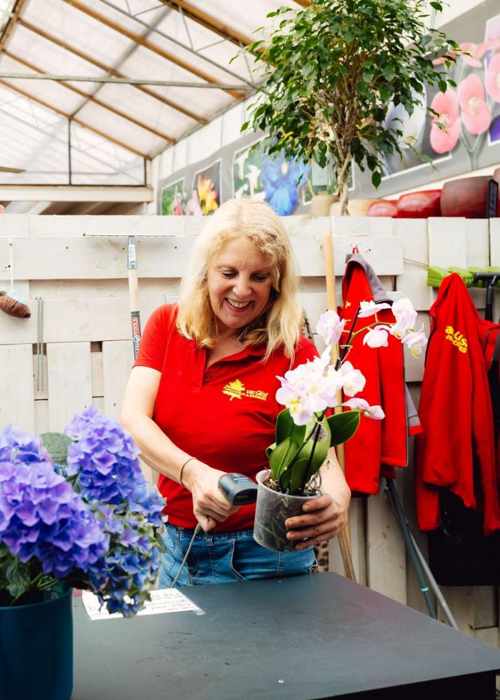 Vrouw achter balie die een barcode van een plant scant.