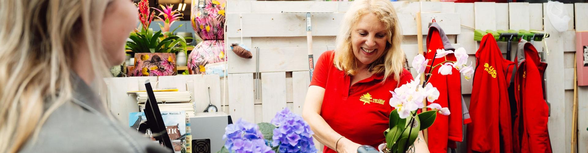Vrouw achter balie die een barcode van een plant scant.