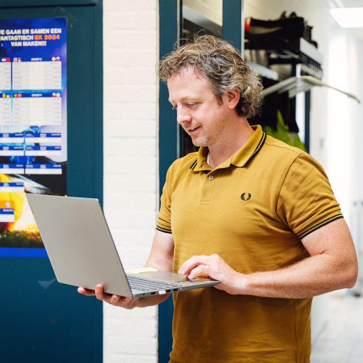 Man met een laptop in zijn hand.