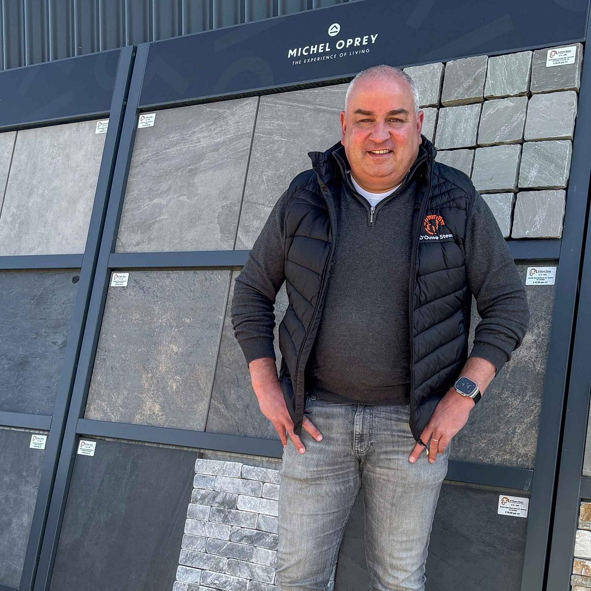 Medewerker van D'ouwe Steen in de showroom met keramische tegels en natuursteen voor tuin en terras.