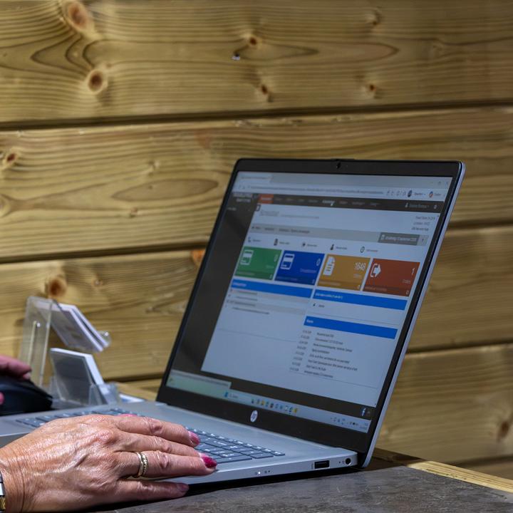 Close-up van handen bij een laptop met een digitaal dashboard op het scherm.