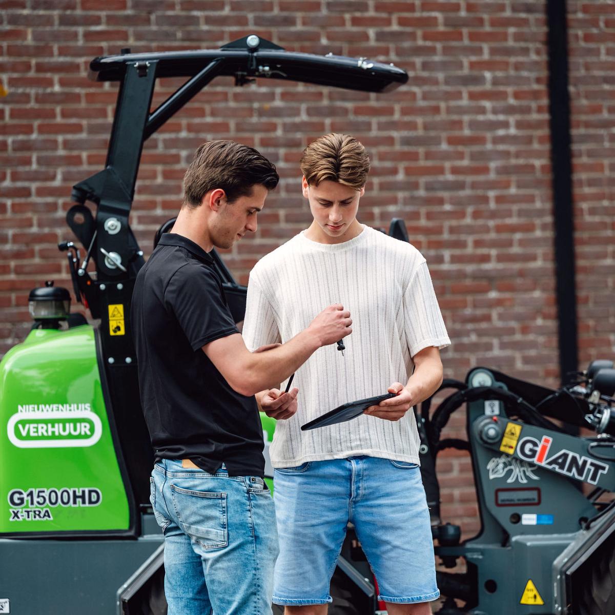 Twee medewerkers bekijken samen informatie op een tablet bij verhuurmachines