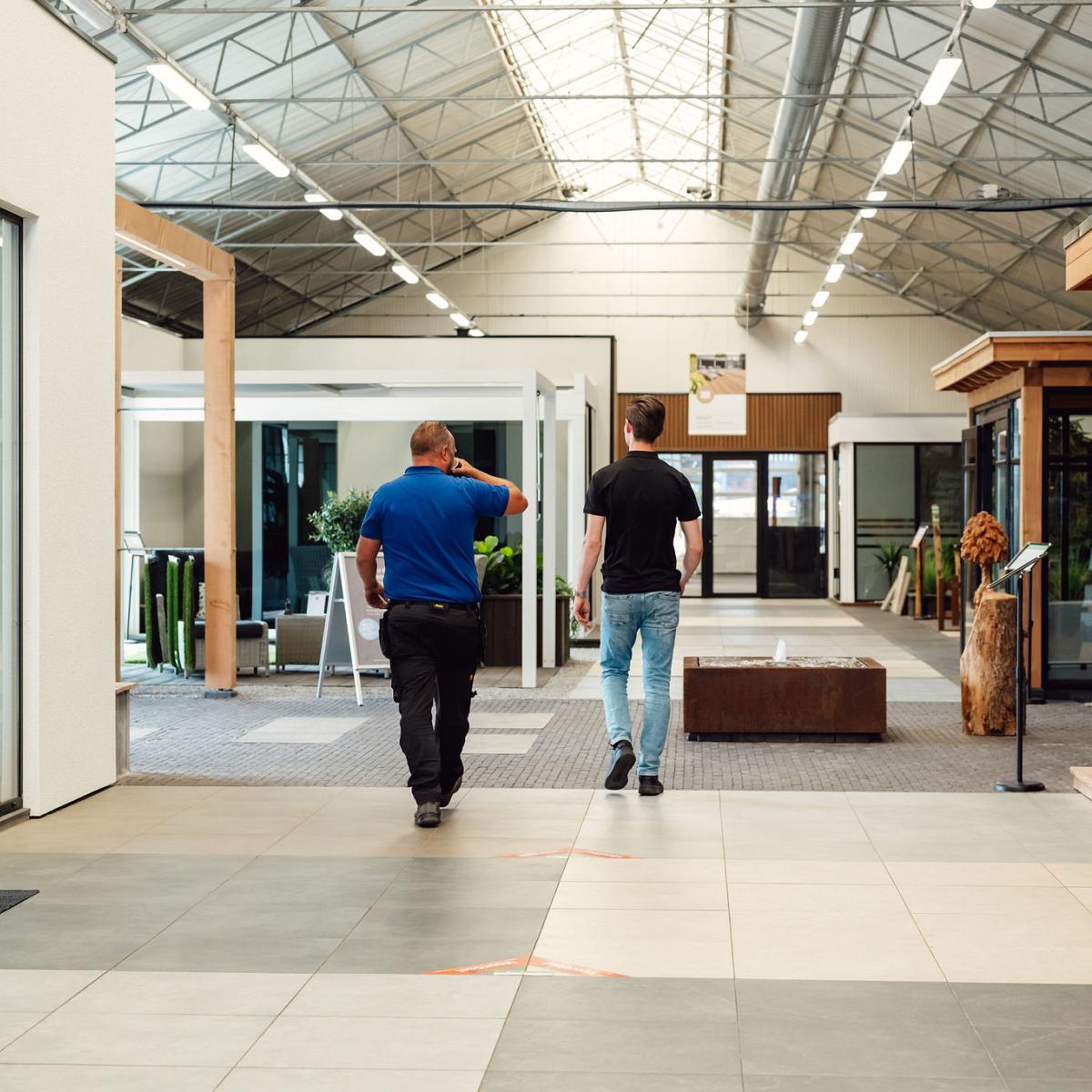 Medewerker en klant lopen door de showroom van Nieuwenhuis Buitenleven