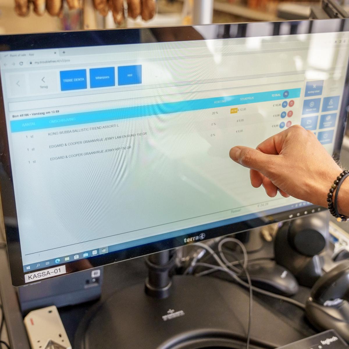 De afbeelding toont een hand die naar een computerscherm wijst met een grafische gebruikersinterface met verschillende informatie en tabbladen.
