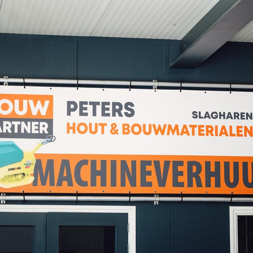 BouwPartner Peters in Slagharen biedt hout, bouwmaterialen en machineverhuur aan, weergegeven op een reclamebord boven hun ingang.