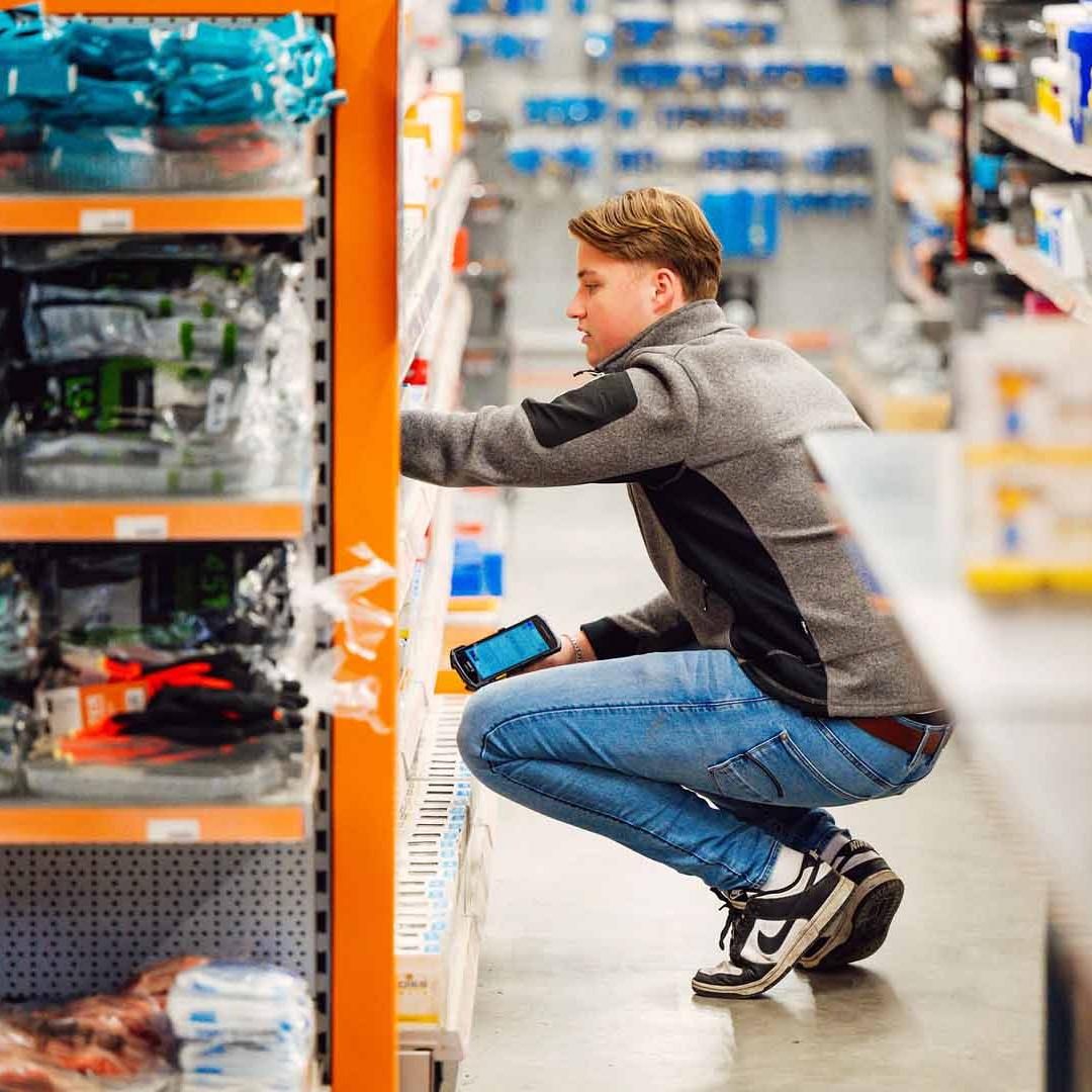 Man is aan het werk in een schap met bouw spullen met in zijn rechterhand een scanner.