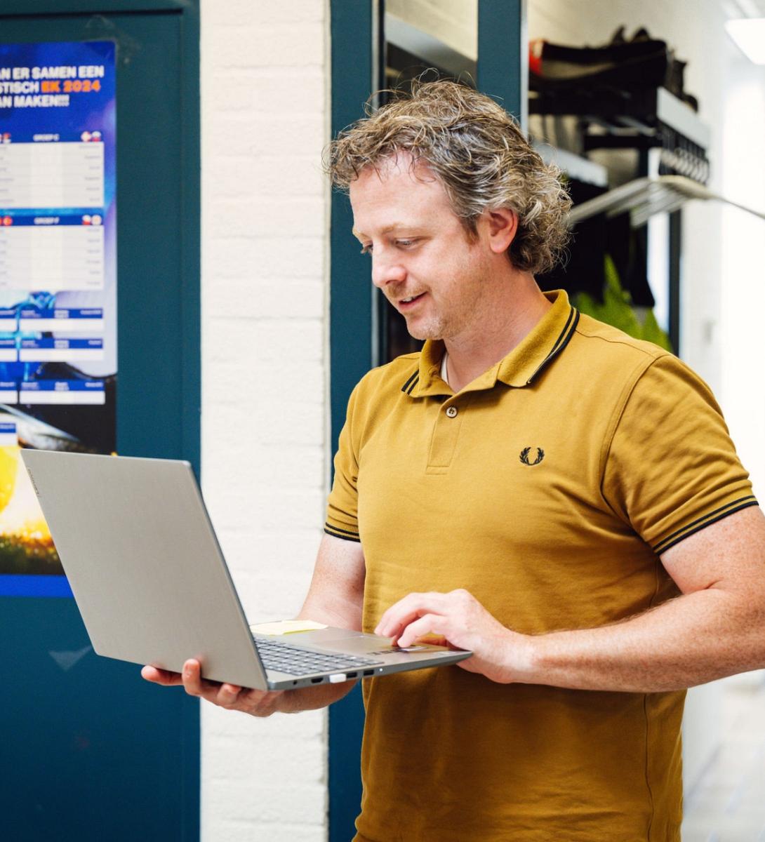 Man met een laptop in zijn hand.