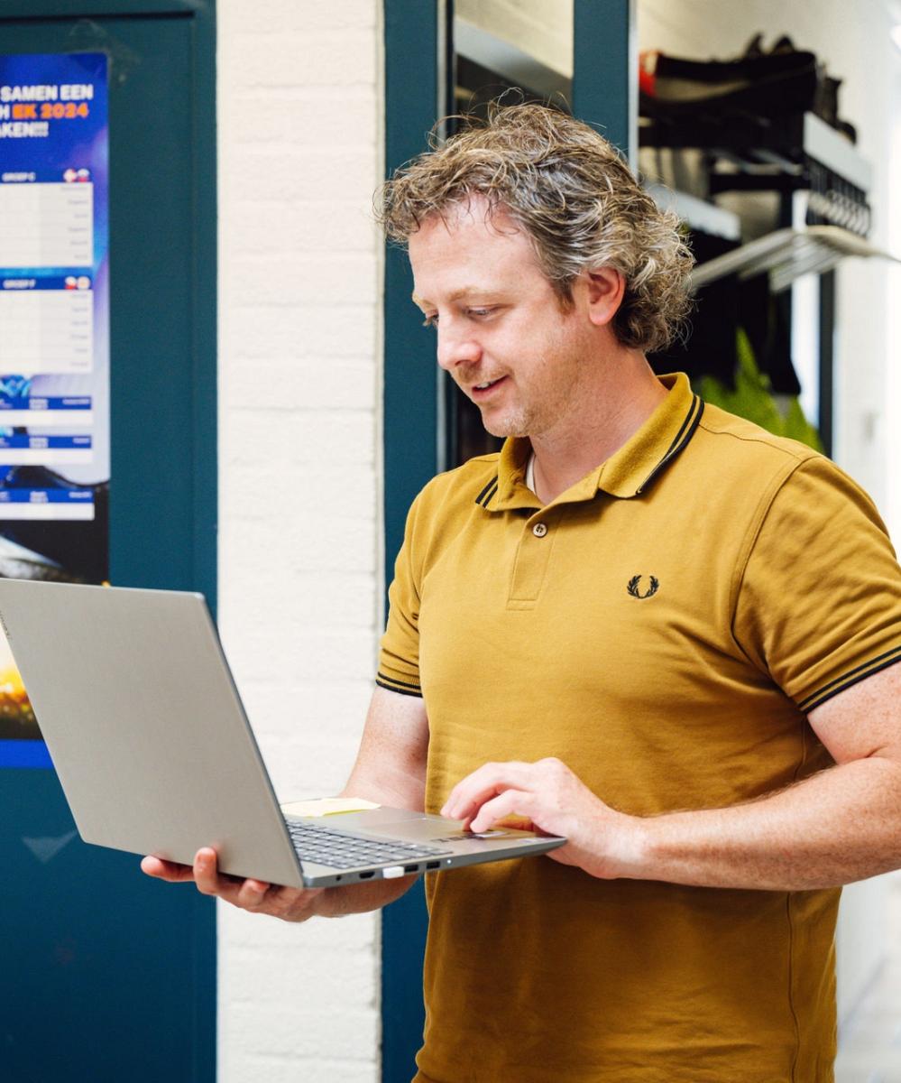 Man met een laptop in zijn hand.
