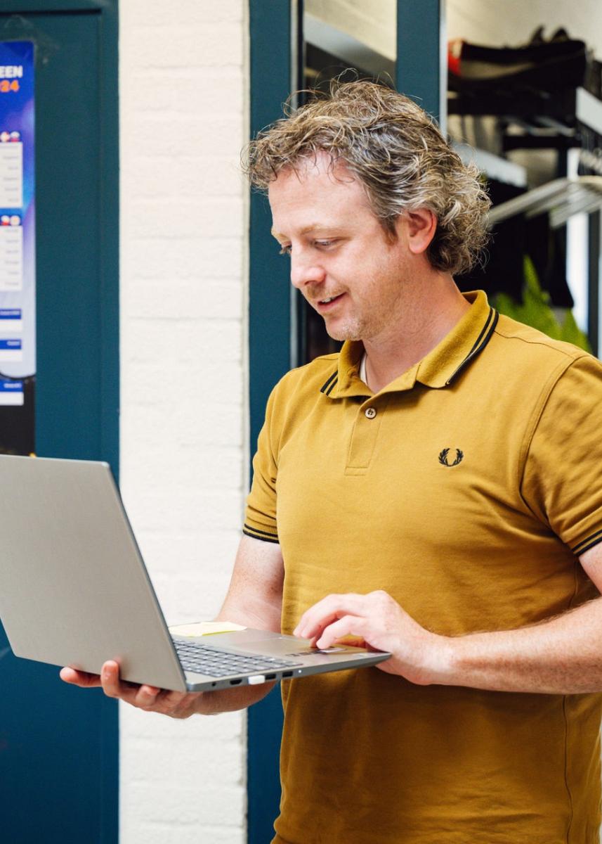 Man met een laptop in zijn hand.