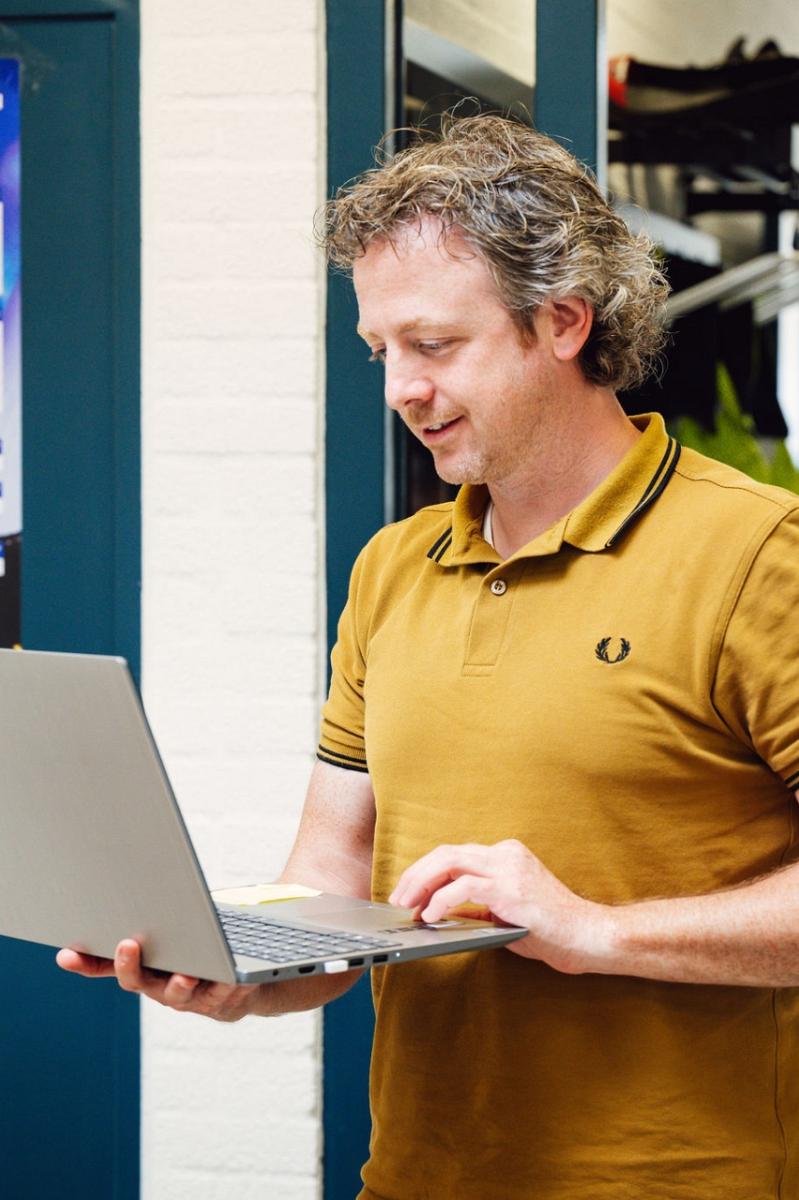 Man met een laptop in zijn hand.