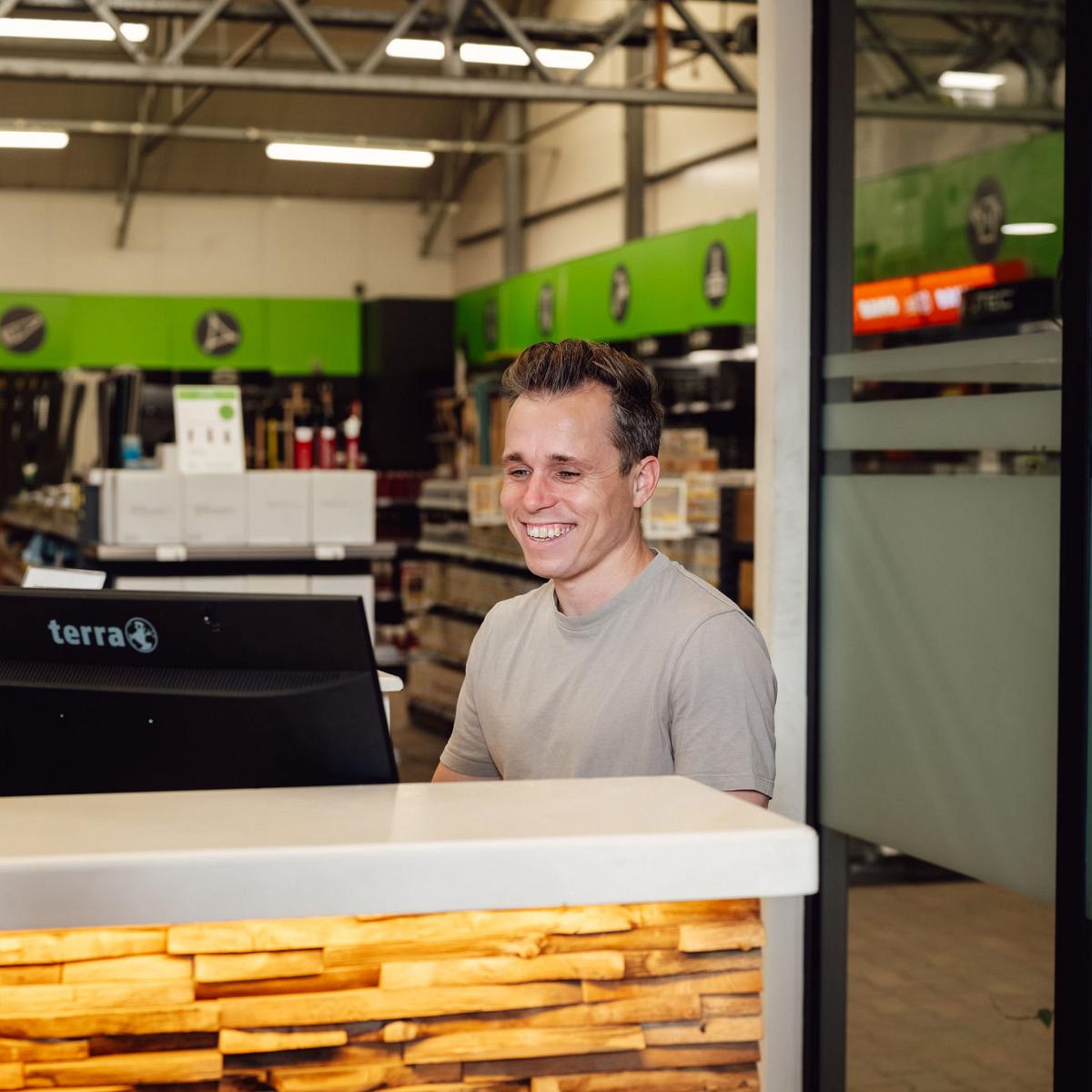 Medewerker werkt achter de balie in de showroom van Nieuwenhuis Buitenleven