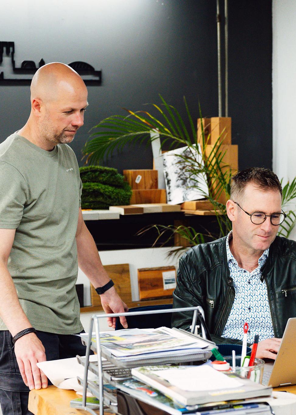 Twee personen overleggen bij een laptop in een showroom voor bouwmaterialen
