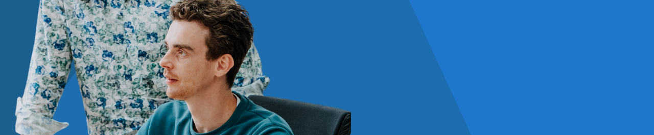 Twee medewerkers van Smart Trade bij een computer, met een blauwe achtergrond.