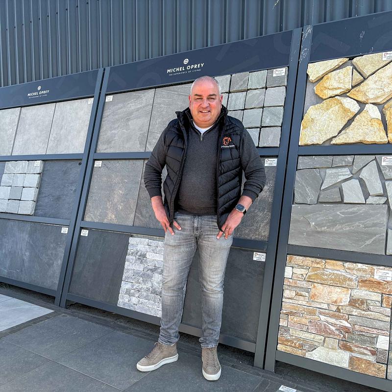 Medewerker van D'ouwe Steen in de showroom met keramische tegels en natuursteen voor tuin en terras.
